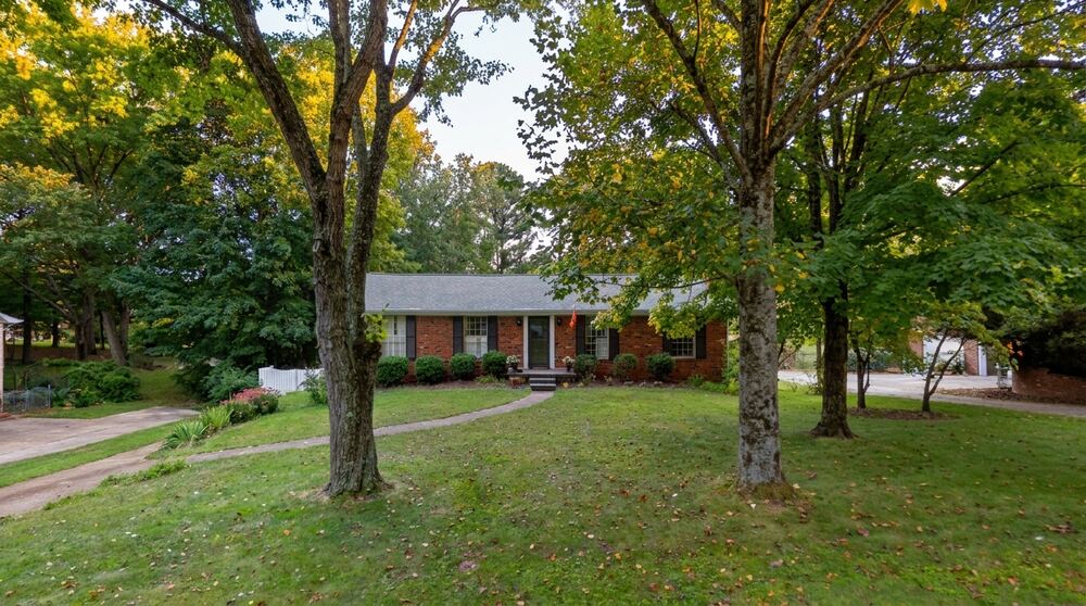 A brick ranch house on Ramsgate Drive under tall shade trees